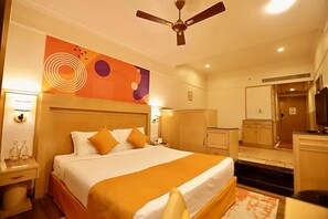 A hotel room with a large bed, a ceiling fan, a wardrobe, and a desk with a chair. - Ira By Orchid Mumbai - T2 International Airport (Mumbai)