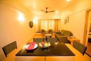 A hotel room with a dining table, chairs, a sofa, and a ceiling fan. - Ira By Orchid Mumbai - T2 International Airport (Mumbai)