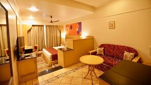 A compact living space with a sofa, a small table, a kitchenette, and a ceiling fan. - Ira By Orchid Mumbai - T2 International Airport (Mumbai)