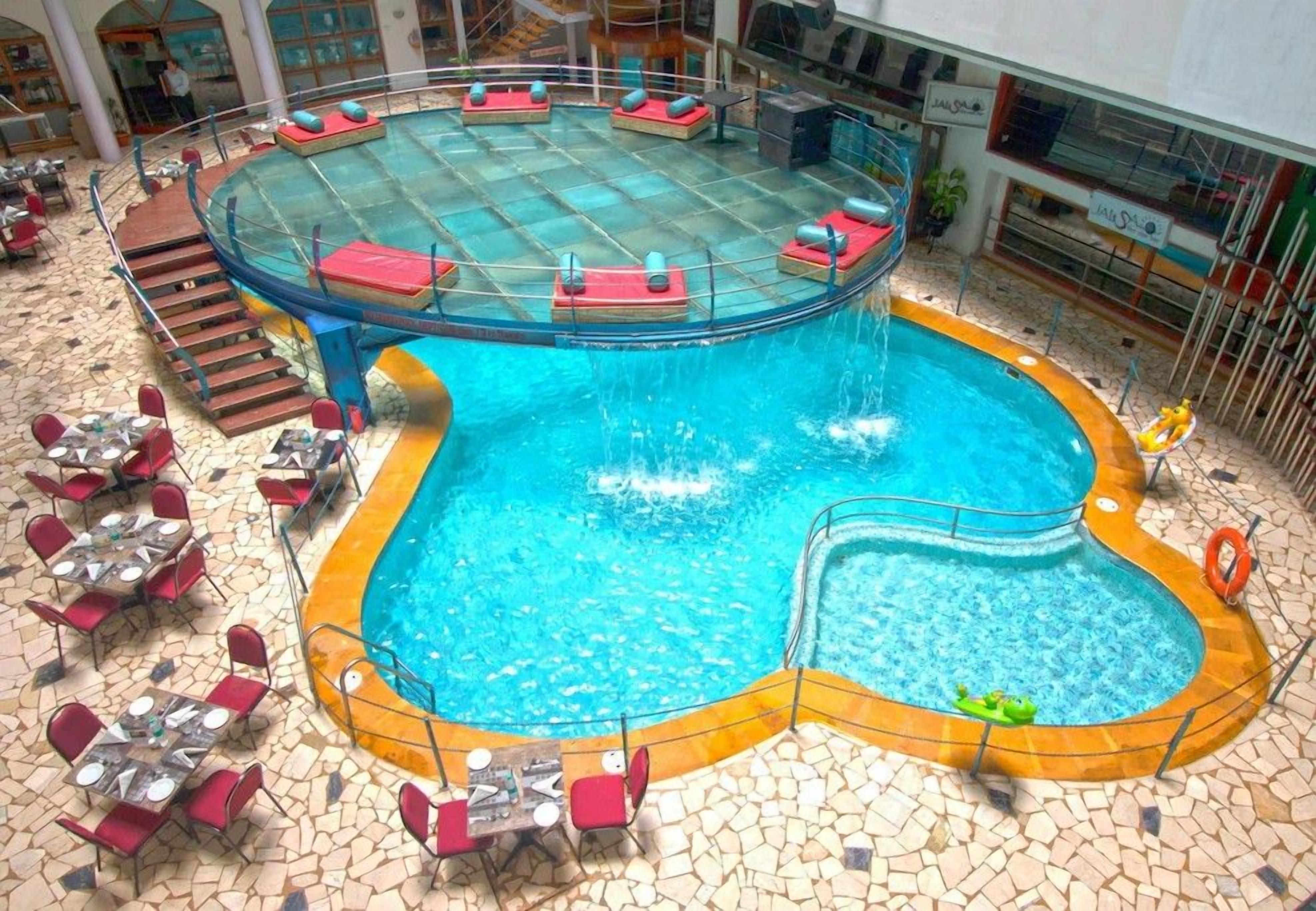 A pool area with a circular hot tub, lounge chairs, and tables.