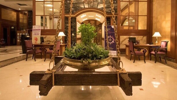 A lobby with a central swing chair, a chandelier, and a large potted plant. - Ira By Orchid Mumbai - T2 International Airport (Mumbai)