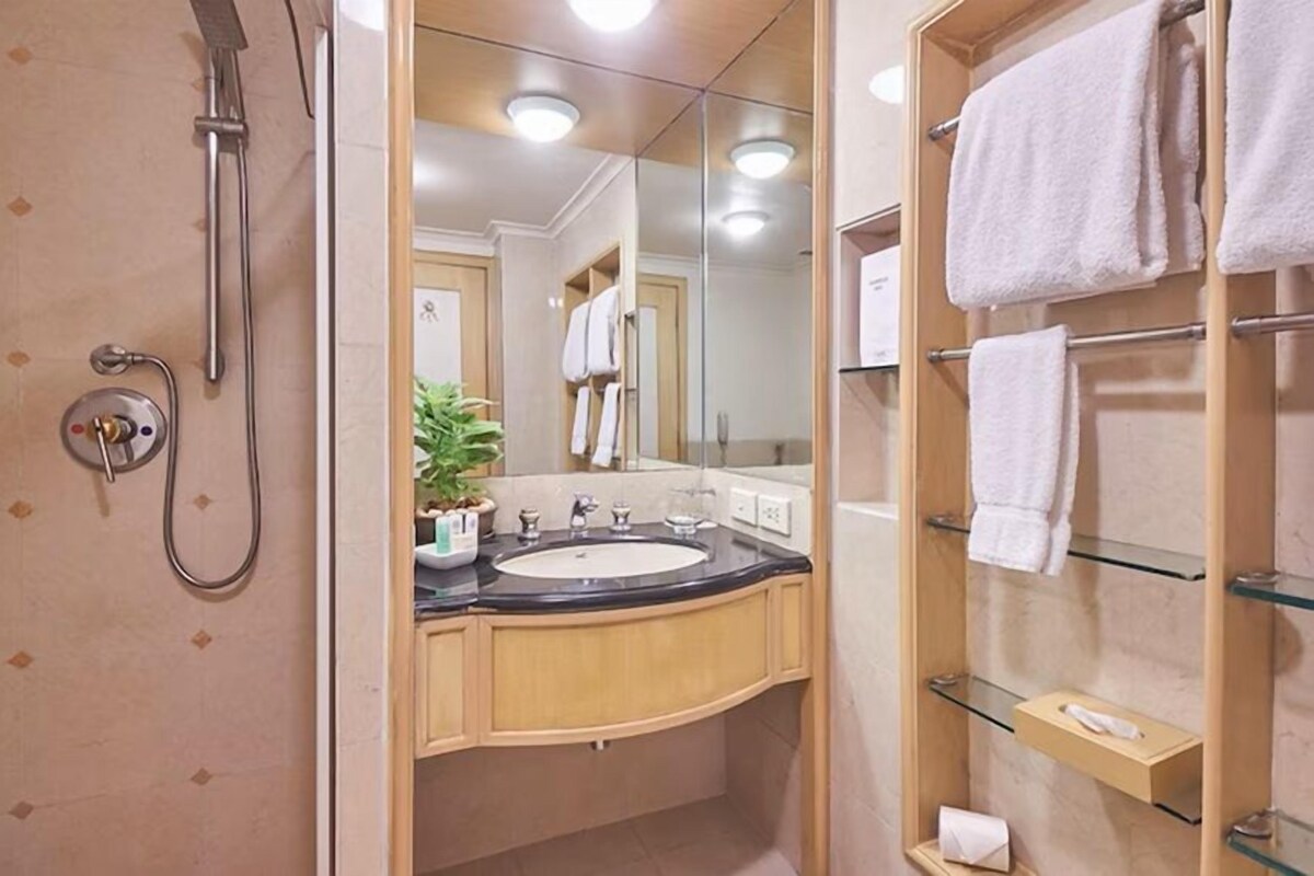A bathroom with a shower, sink, and glass shelves for towels.