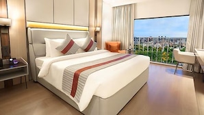 Une chambre d’hôtel moderne avec un grand lit, un bureau et une vue sur la ville.