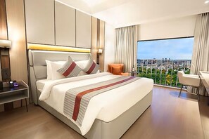 A modern hotel room with a large bed, a desk, and a view of the city. - The Orchid Chandigarh (Dera Bassi)