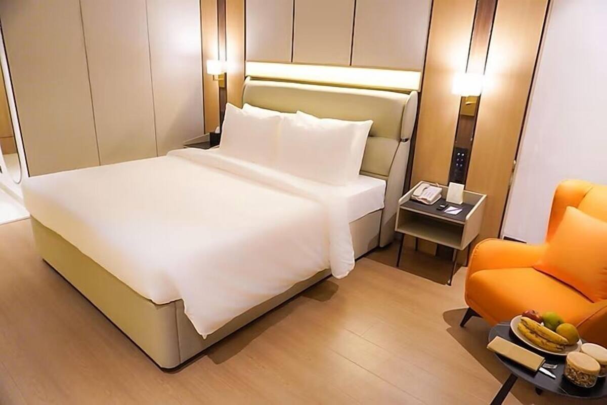 A hotel room with a bed, bedside table, and an orange armchair.