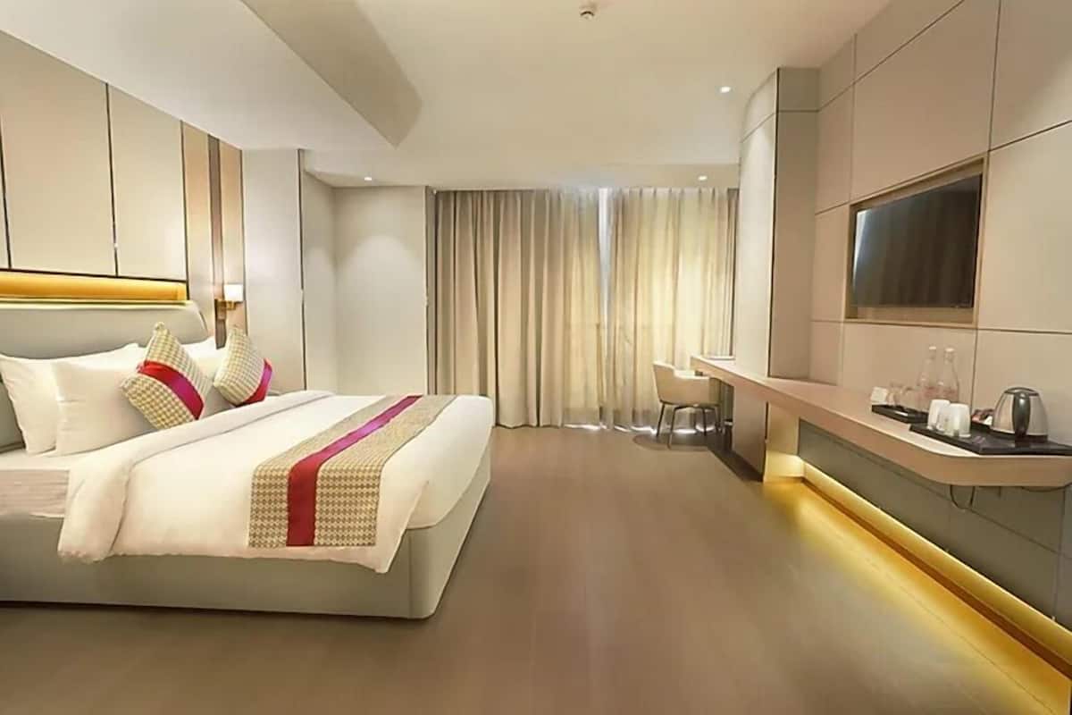 A modern hotel room with a large bed, a desk, and a TV.