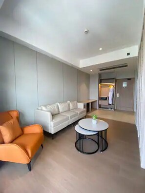 Un salon moderne avec un canapé blanc, un fauteuil orange et une table basse ronde.