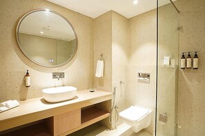 Ein modernes Badezimmer mit rundem Spiegel, Waschbecken, Dusche und Toilette.