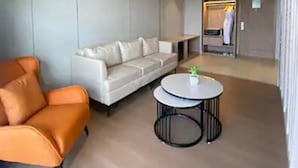 Un salon moderne avec un canapé blanc, un fauteuil orange et une table basse ronde.