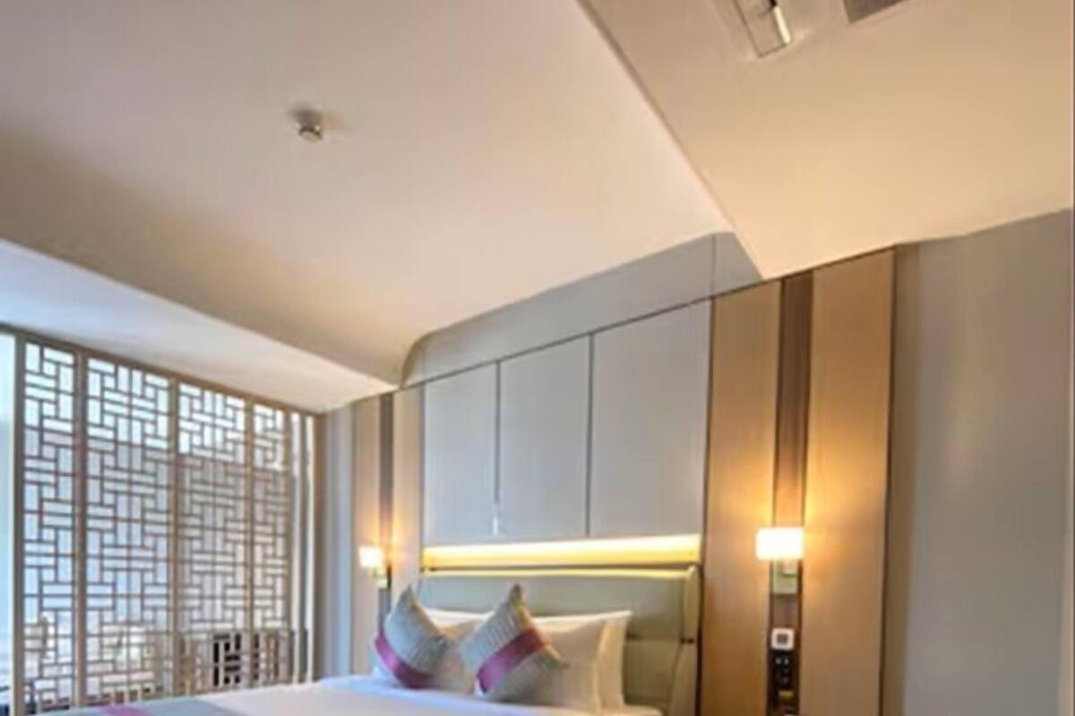 A modern hotel room with a large bed, a seating area, and a decorative screen.