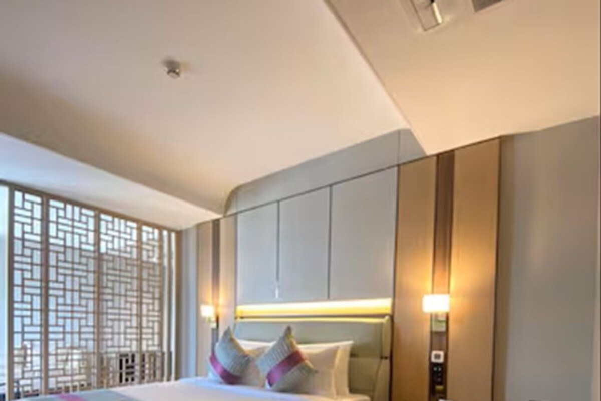 A modern hotel room with a large bed, a seating area, and a decorative screen.