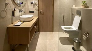 Une salle de bain moderne avec une douche à parois de verre, un meuble-lavabo en bois, un miroir rond et des toilettes.