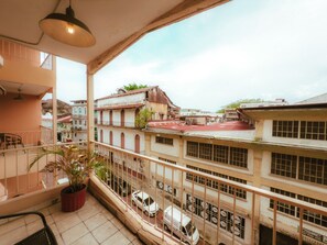 Een balkon met uitzicht op een stadsgezicht, inclusief gebouwen en geparkeerde auto's.