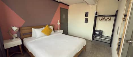 Un dormitorio ordenado con una cama de madera, ropa de cama blanca, una lámpara de noche y una mesita con lámpara.