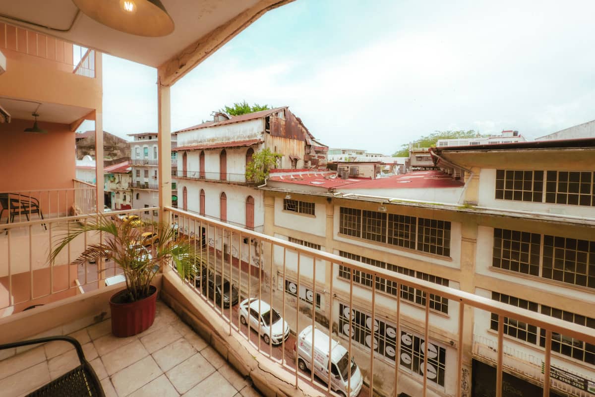 Een balkon met uitzicht op een stadsgezicht, inclusief gebouwen en geparkeerde auto's.