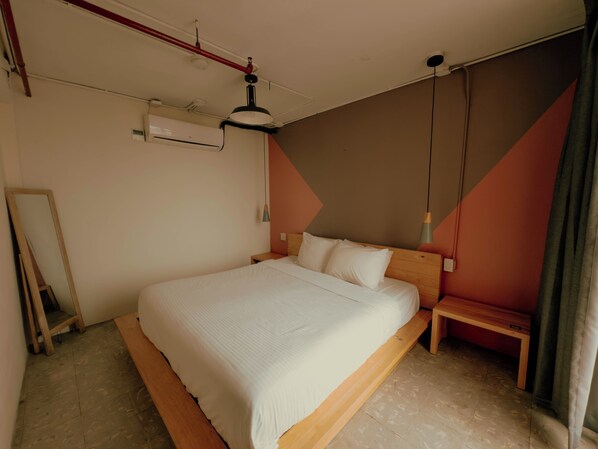Un dormitorio con una cama grande, cabecera de madera, mesita de noche, lámpara colgante y aire acondicionado instalado en la pared.