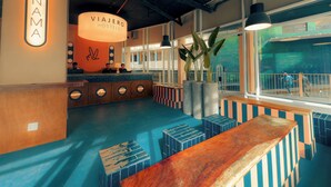 A modern hotel lobby with a reception desk, a large illuminated sign for 'Panama Viajeros Hostels', and a large window with a view of the interior. - Viajero Panama (Panama City)