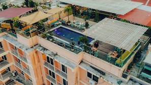 Un área de piscina en la azotea con diversas opciones de asientos y vistas de los edificios circundantes.