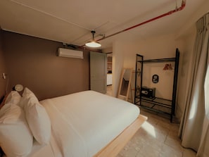 Un dormitorio con cama, aire acondicionado, espejo y armario.