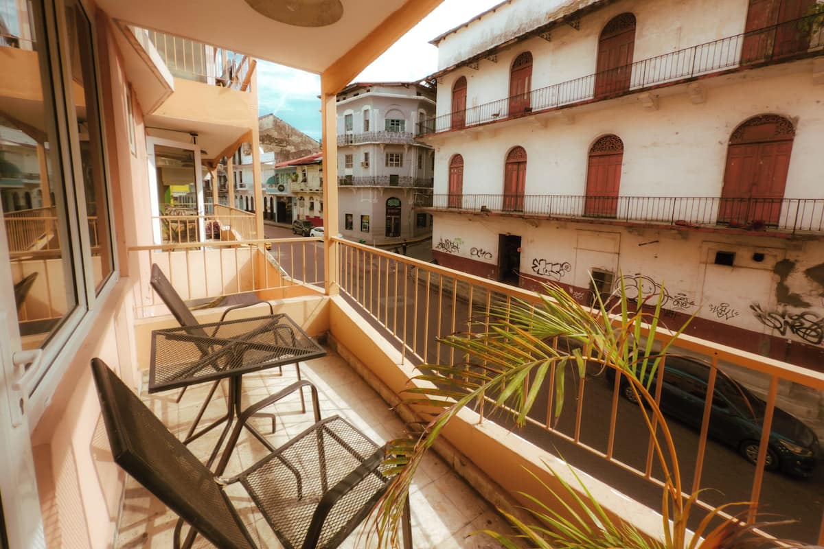 Een balkon met metalen stoelen en een potplant.