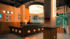 Een receptiebalie met een bord waarop 'VIAJER HOSTEL' staat en een overzicht van voorzieningen.