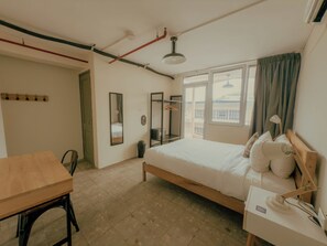 A bedroom with a bed, bedside table, lamp, and a window with curtains. - Viajero Panama (Panama City)