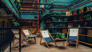 A cozy indoor seating area with wooden chairs and tables, surrounded by shelves with books and decorative items. - Viajero Panama (Panama City)