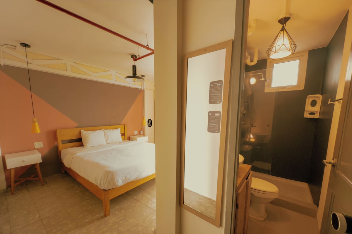 Un dormitorio con cama, mesita de noche y lámpara colgante.