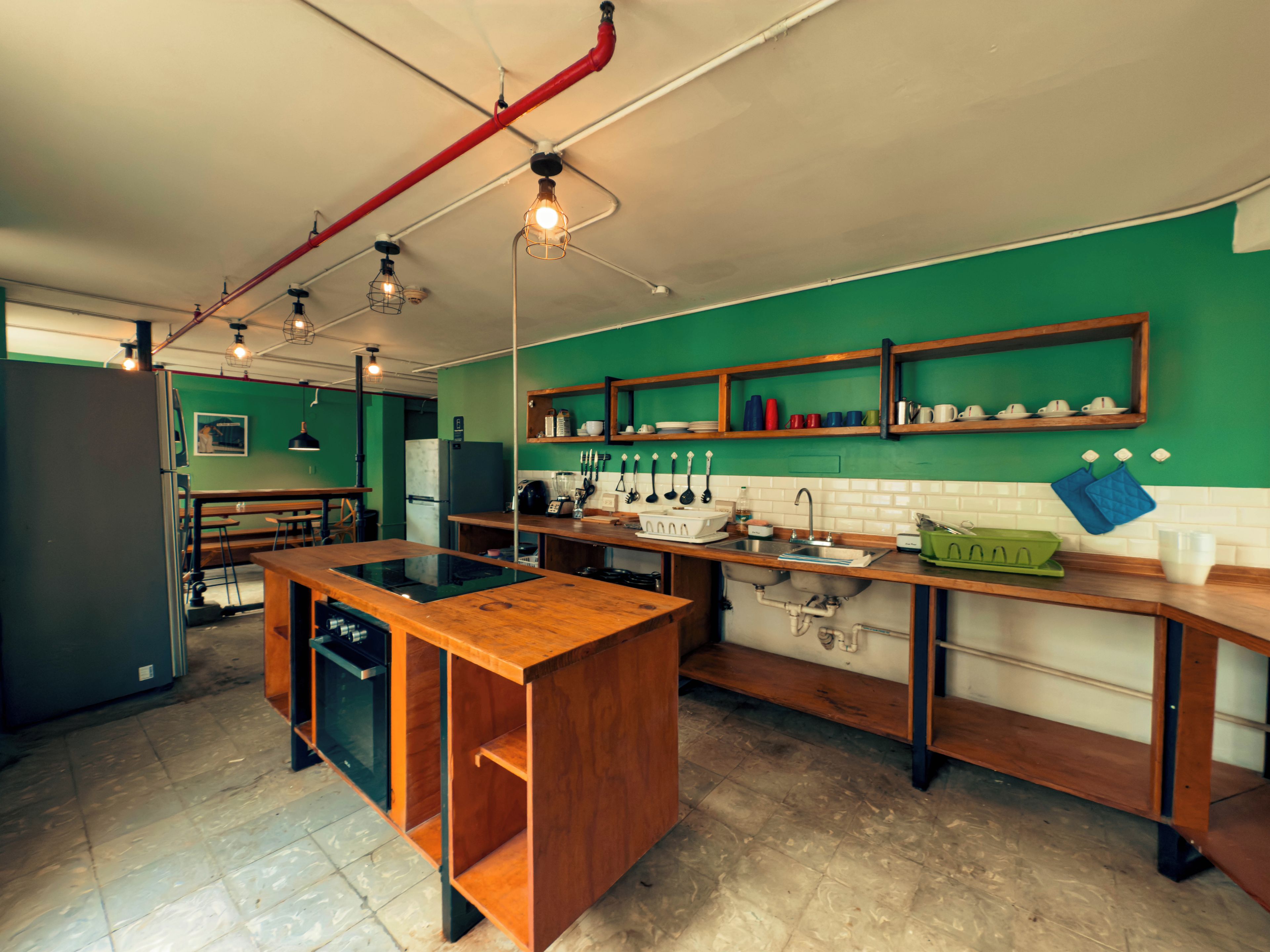 Une cuisine moderne dotée d’un îlot central, de plans de travail en bois et d’un revêtement mural vert.