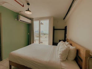 A hotel room with a bed, a window with a view of a cityscape, and an air conditioning unit on the wall. - Viajero Panama (Panama City)