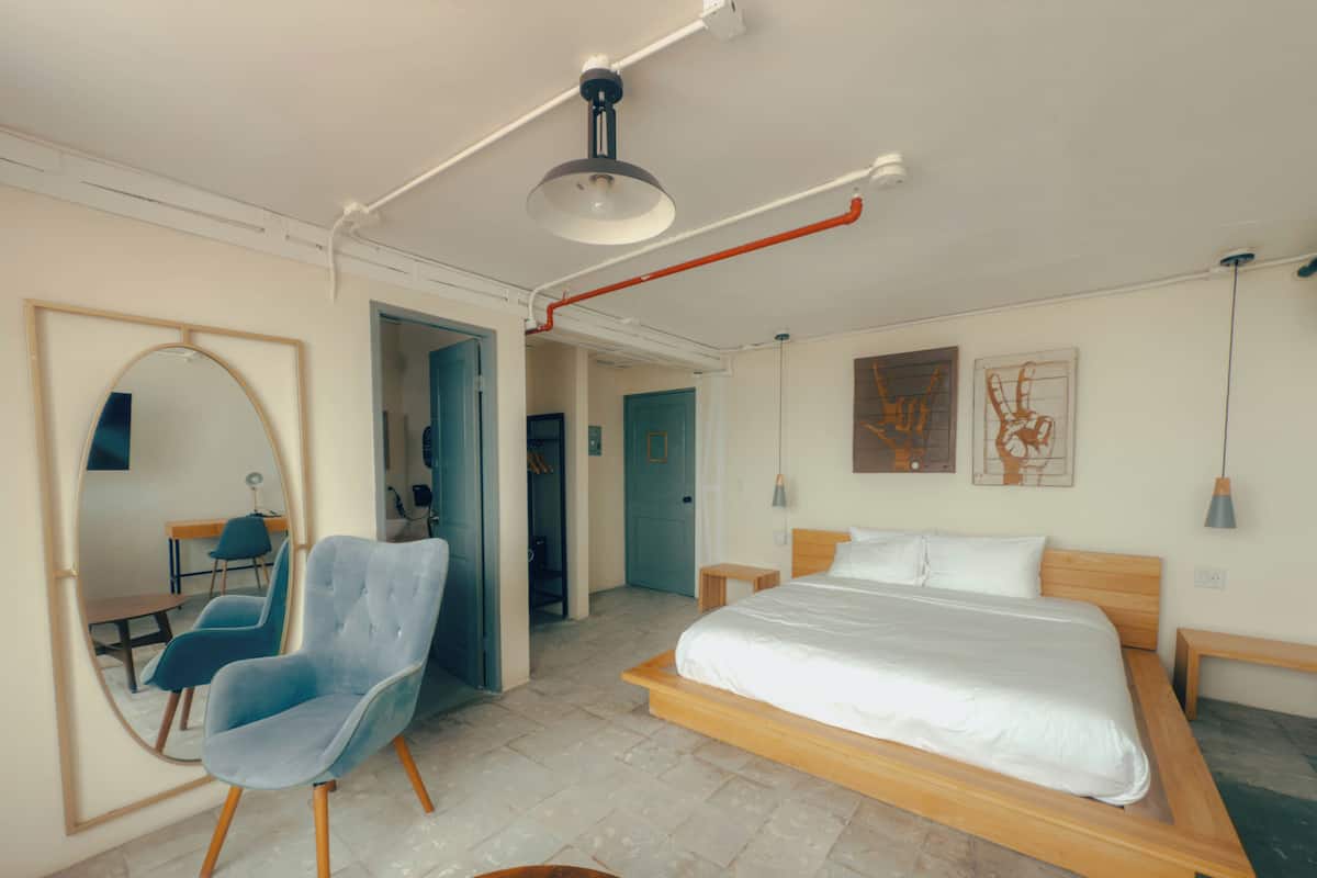 Een moderne slaapkamer met een groot bed, een stoel, een bureau en een spiegel.