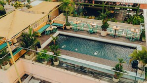 An outdoor swimming pool with surrounding seating areas and potted plants. - Viajero Panama (Panama City)