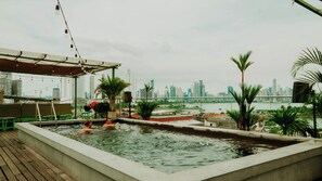 A rooftop swimming pool with a city skyline view, surrounded by greenery and a covered seating area. - Viajero Panama (Panama City)
