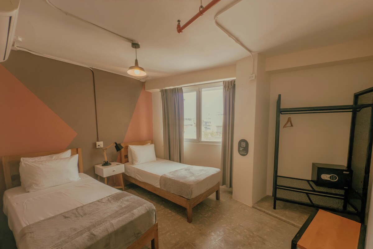 Una habitación de hotel con dos camas, un escritorio, una ventana con cortinas y una litera.