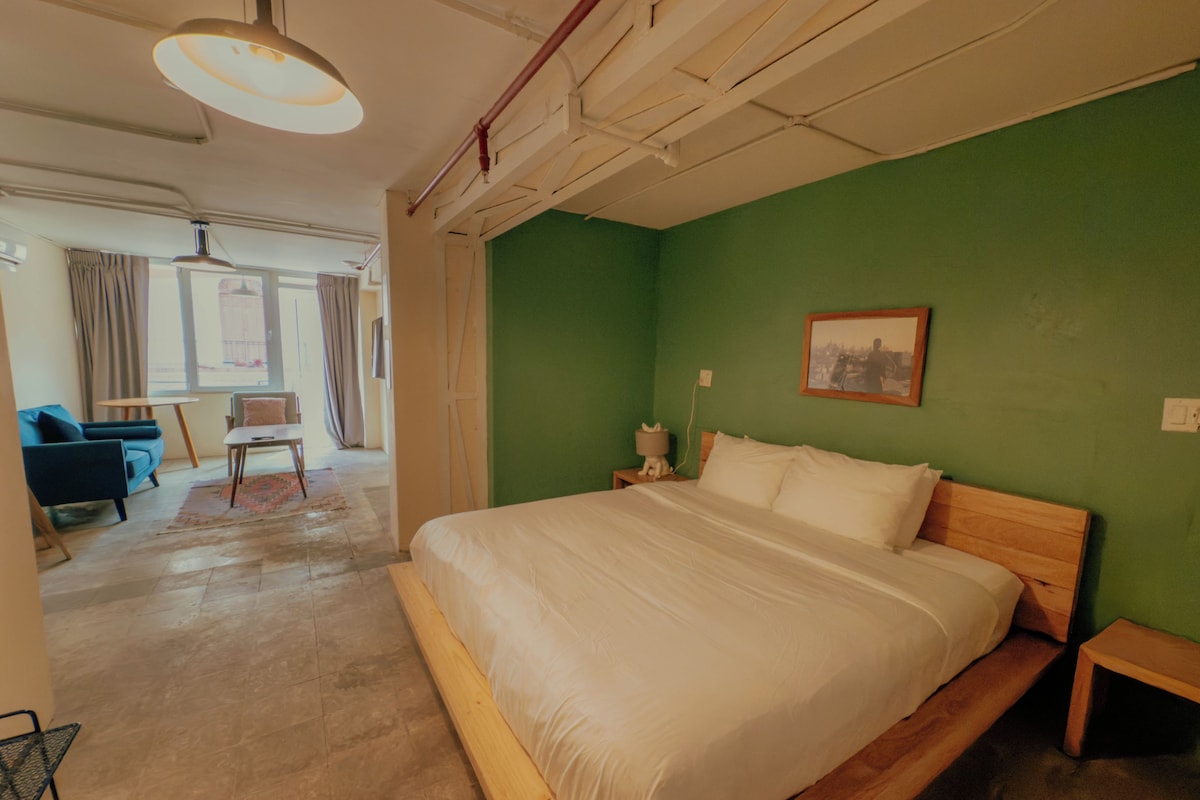 Un dormitorio con una cama grande, una pared verde y una ventana.