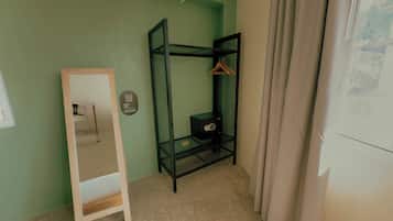Una habitación con literas, una escalera de madera, un mueble pequeño y un estante en la pared con un perchero.