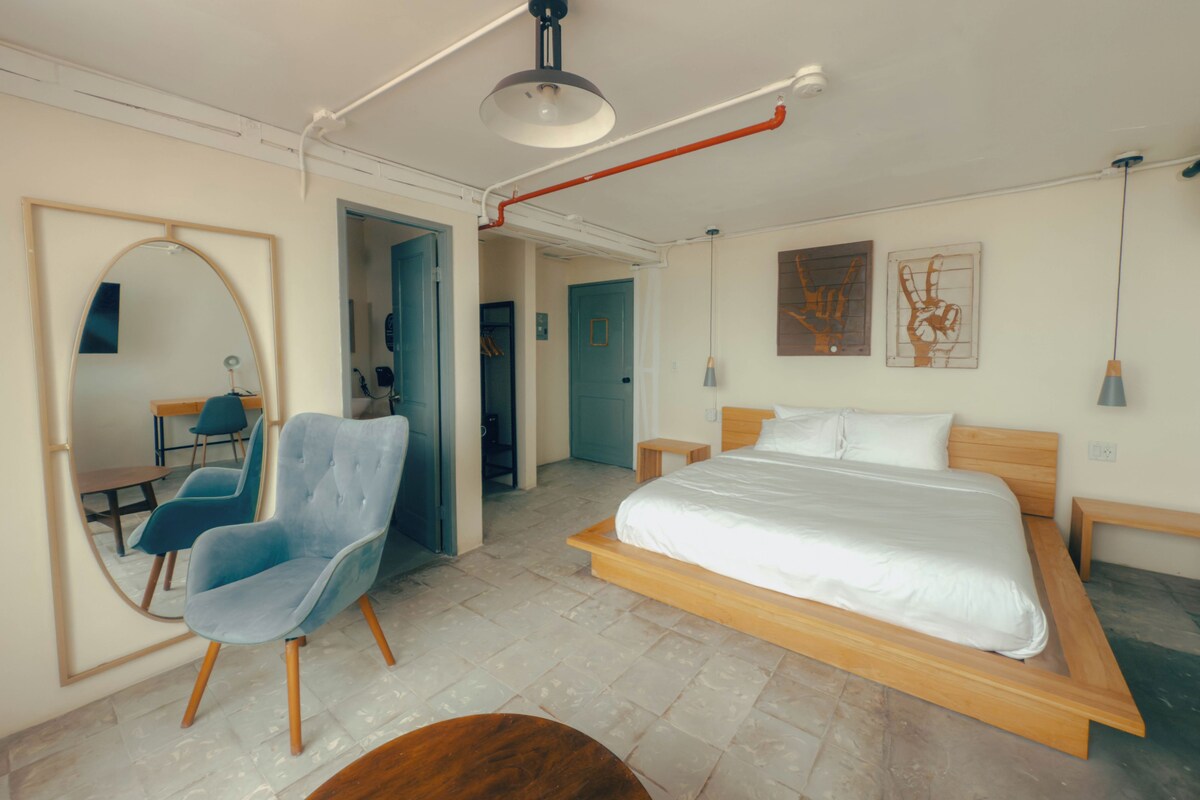 Un dormitorio moderno con una cama grande, una silla, un escritorio y un espejo.