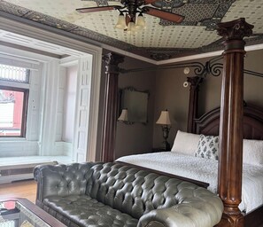 A bedroom with a four-poster bed, a tufted leather sofa, and a ceiling fan. - Villagio Luxury Shops And Hotel (Pittsburgh)