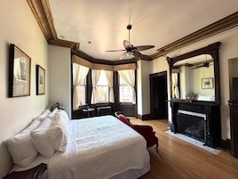 Un dormitorio con una cama grande, chimenea y ventilador de techo.