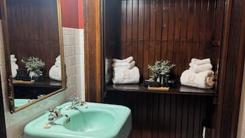 A bathroom with a green sink, wooden vanity, and a mirror.