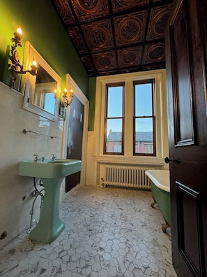 Une salle de bain avec un lavabo vert, un miroir, une fenêtre et une baignoire.