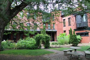 A courtyard with a brick building, a stone bench, and a small table. - Villagio Luxury Shops And Hotel (Pittsburgh)