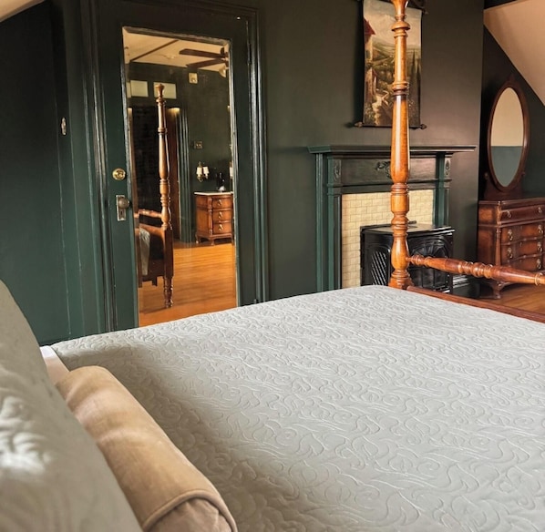 A bedroom with a large bed, a wooden chair, a fireplace, and a mirror. - Villagio Luxury Shops And Hotel (Pittsburgh)