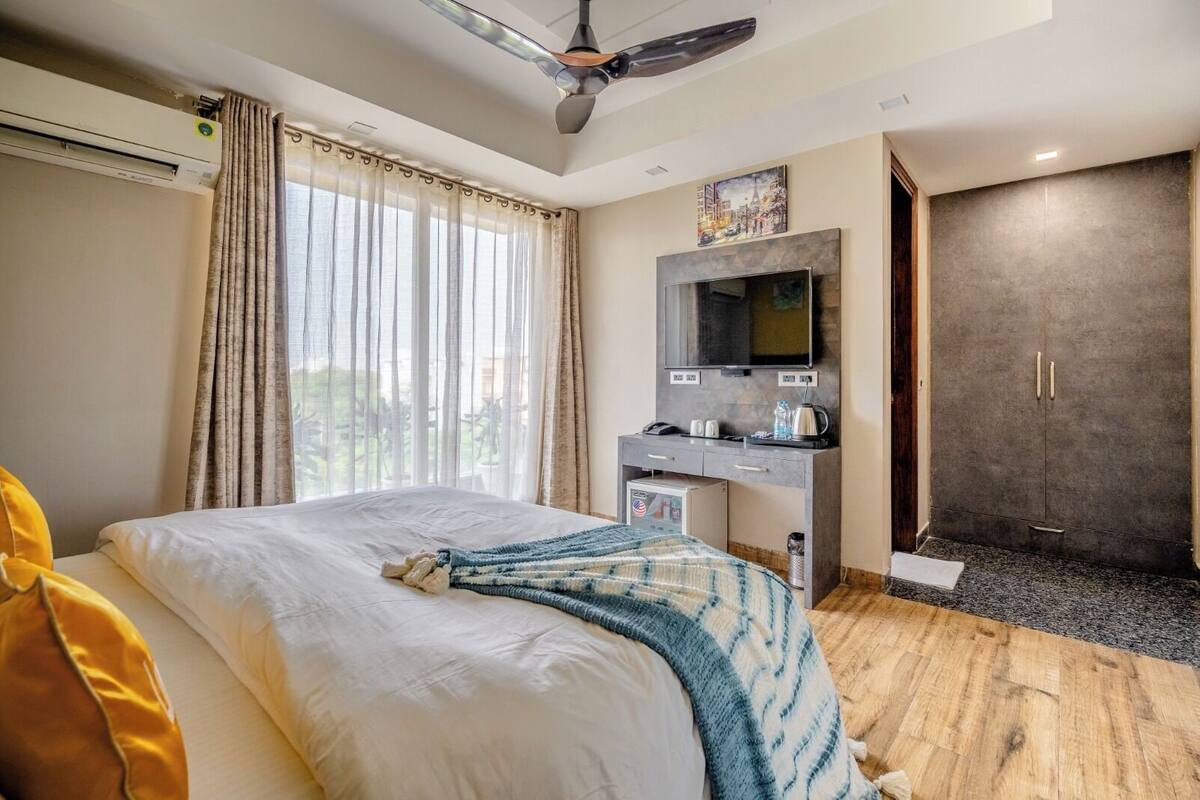 A hotel room with a bed, a desk, a television, and a shower area.