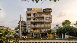 A multi-story building with balconies, a sign for 'arabi restaurant', and a 'Time Free' sign below. - Lime Tree Hotel - Near Medanta Hospital (Gurugram)