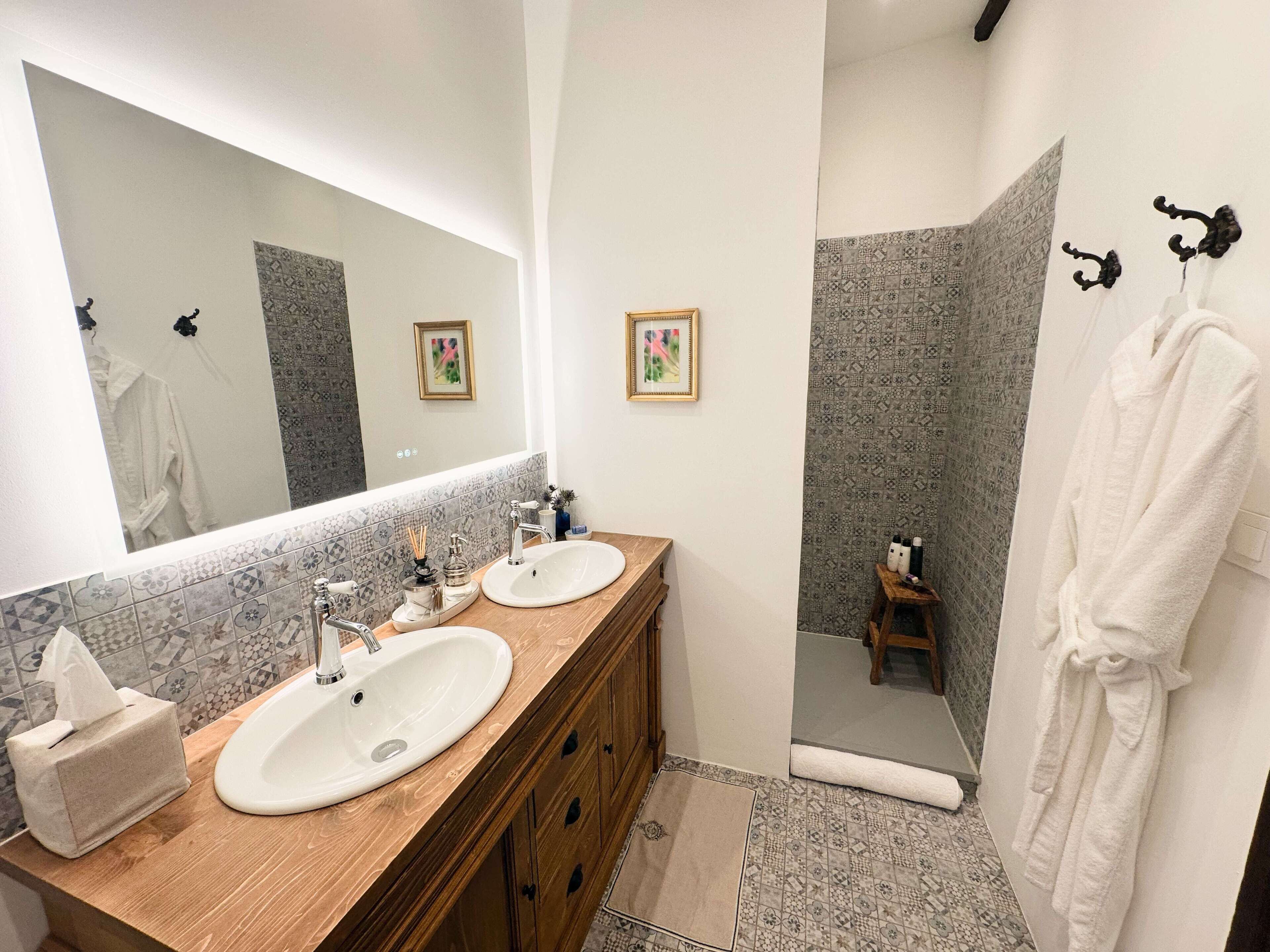 A bathroom with two sinks, a mirror, and a shower area.