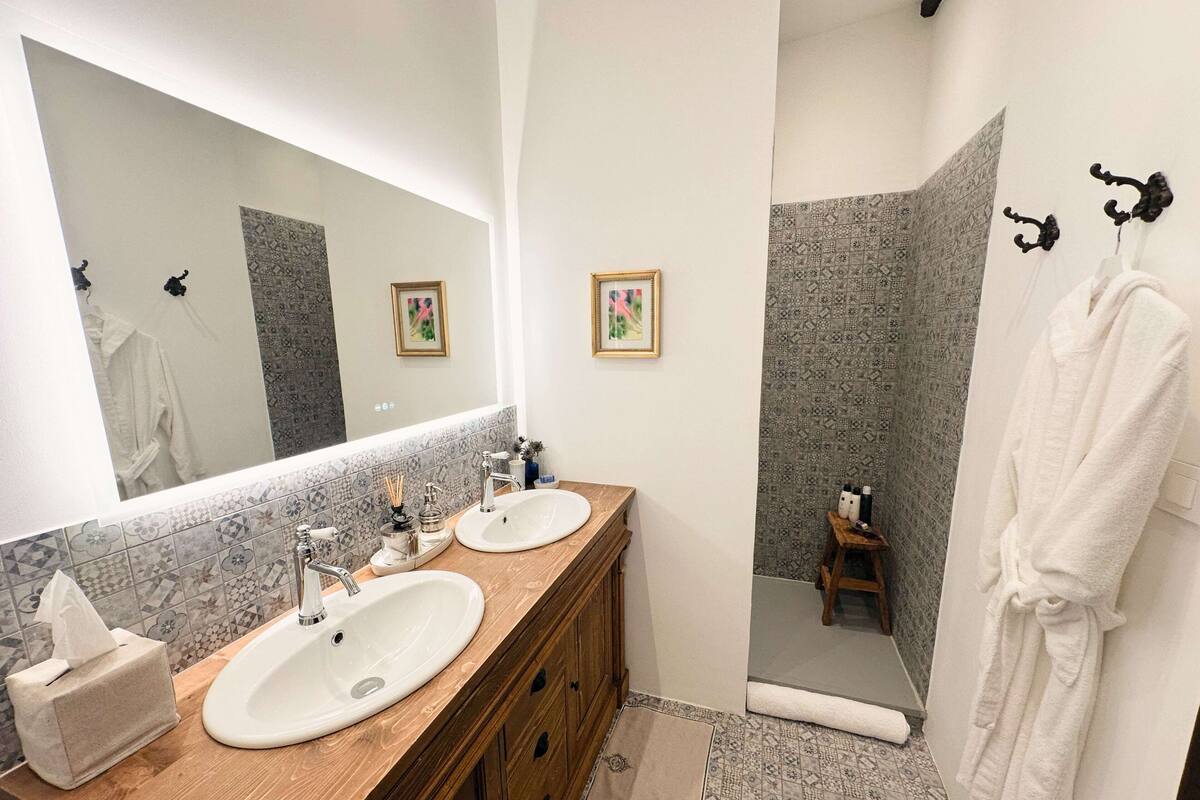 A bathroom with two sinks, a mirror, and a shower area.