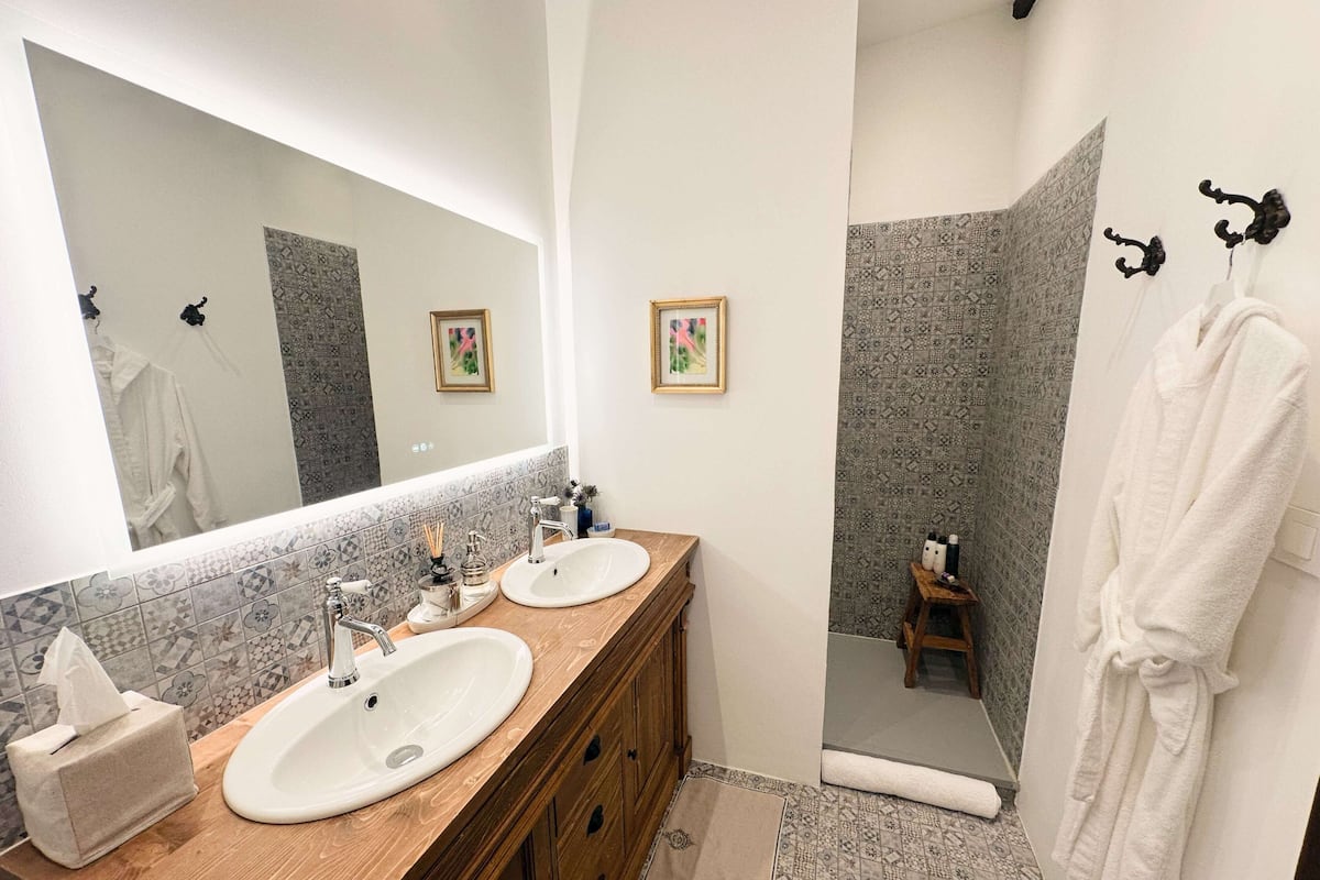 A bathroom with two sinks, a mirror, and a shower area.