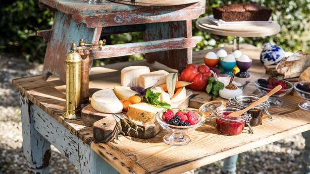 A rustic outdoor table with various cheeses, fruits, and pastries. - Les Manibelles (Amarens)
