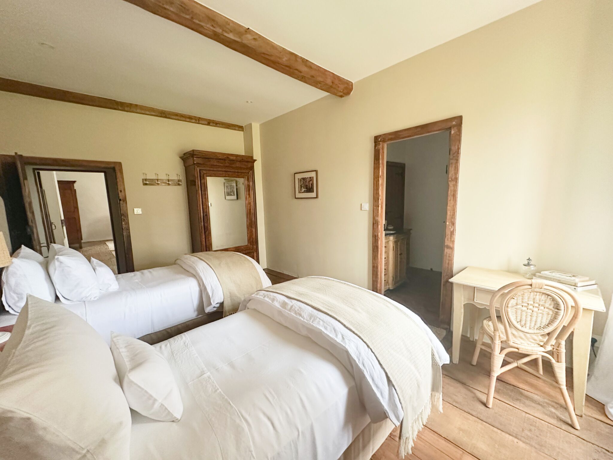 A room with two beds, a desk, a chair, and a mirror.